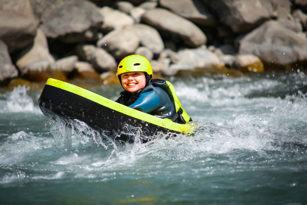 Descente en hydrospeed pour les enfants sur de l'eau vive des Alpes avec le sourire.