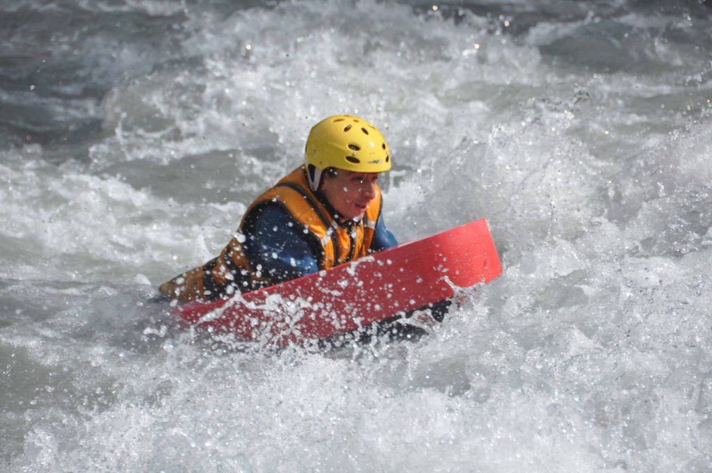 un flotteur rouge qui passe une vague d'une rivière dans les Alpes.