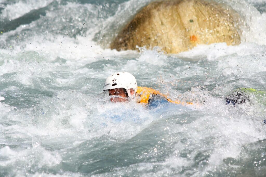 un hydrospeed qui disparais dans la rivière avec son casque blanc sur une rivière des alpes
