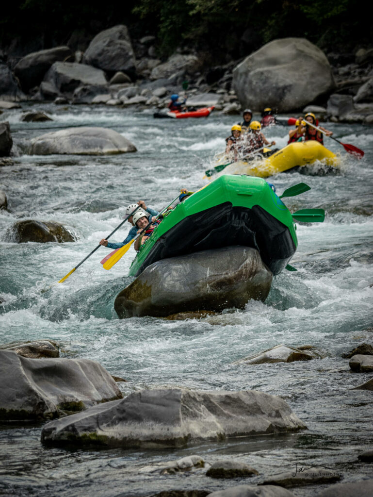 Rafting EVG - Un raft vert qui monte sur un cailloux pour une faire une figure freestyle.
