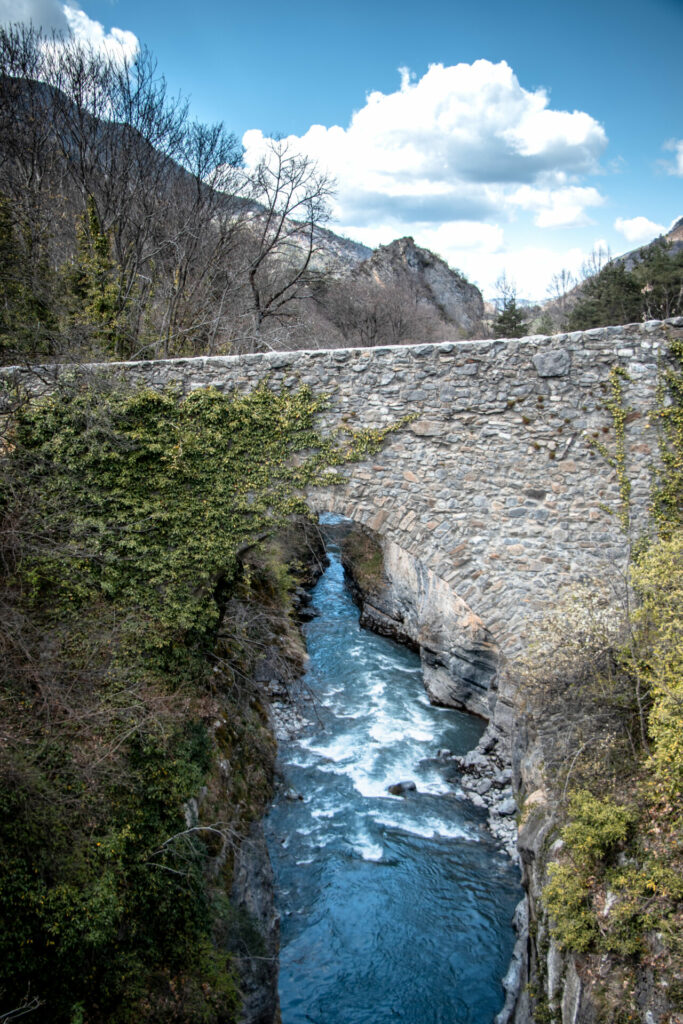 le pont romain du lauzet ubaye sous un ciel bleu. On peut apercevoir l'Ubaye 40 mètres en dessous
